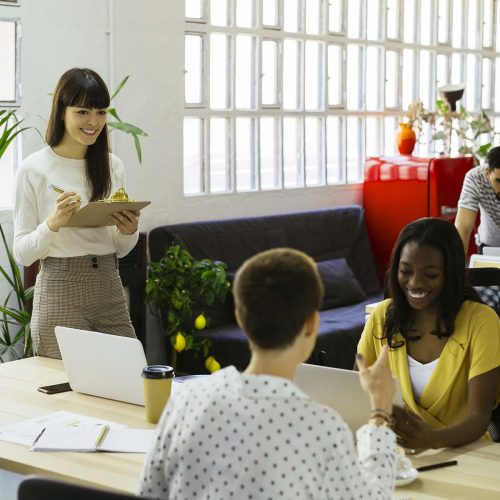 smiling-woman-with-clipboard-among-colleagues-in-o-YHDP3P7.jpg